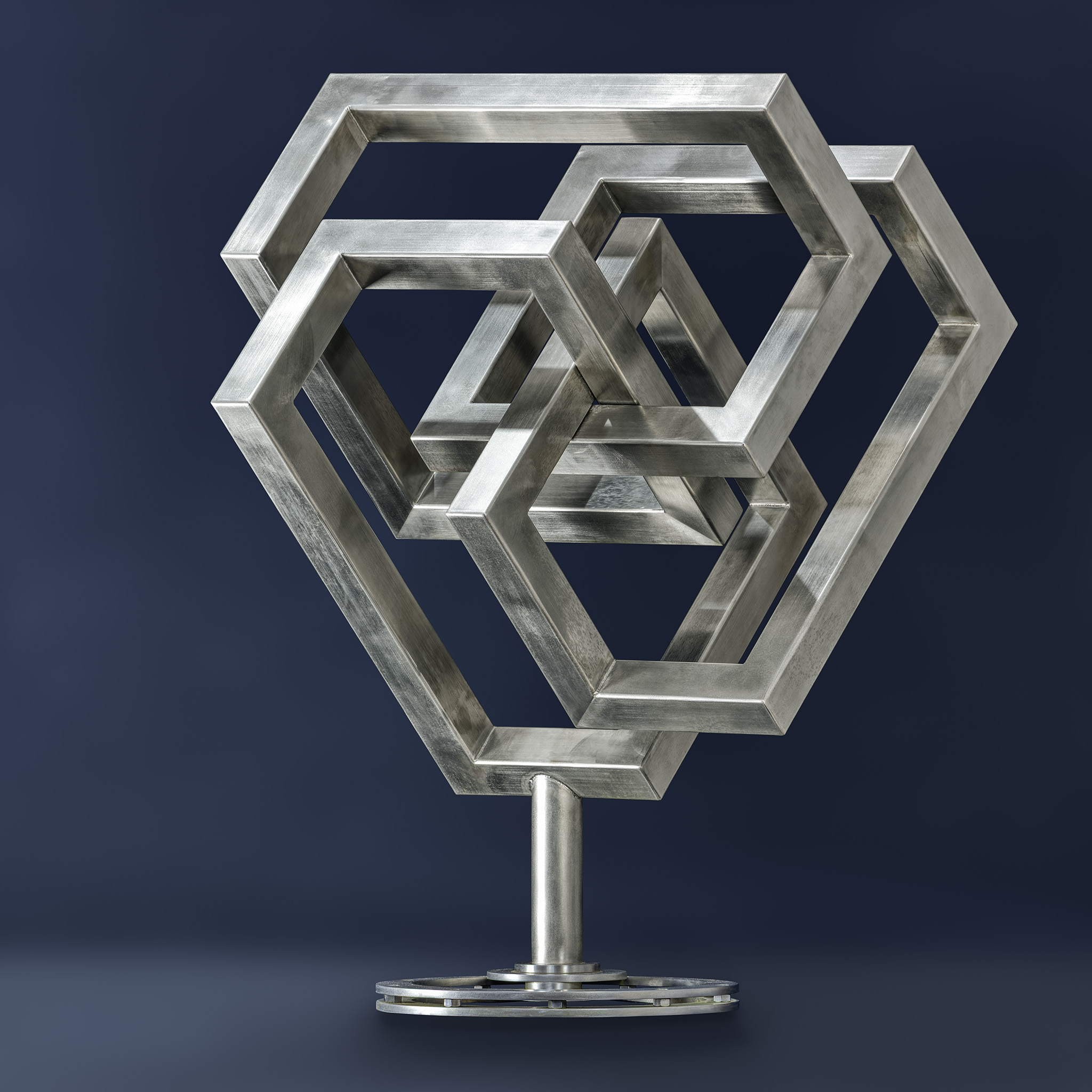 Stainless steel sculpture composed of interlocking geometric frames on stand